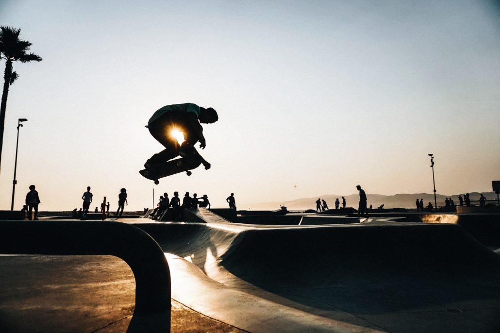 Deutsch: "Surfer reitet die perfekte Welle und Skater performt Tricks am Strand – der Lifestyle von Freiheit und Flow." Englisch: "Surfer riding the perfect wave and skater performing tricks on the beach – the lifestyle of freedom and flow."